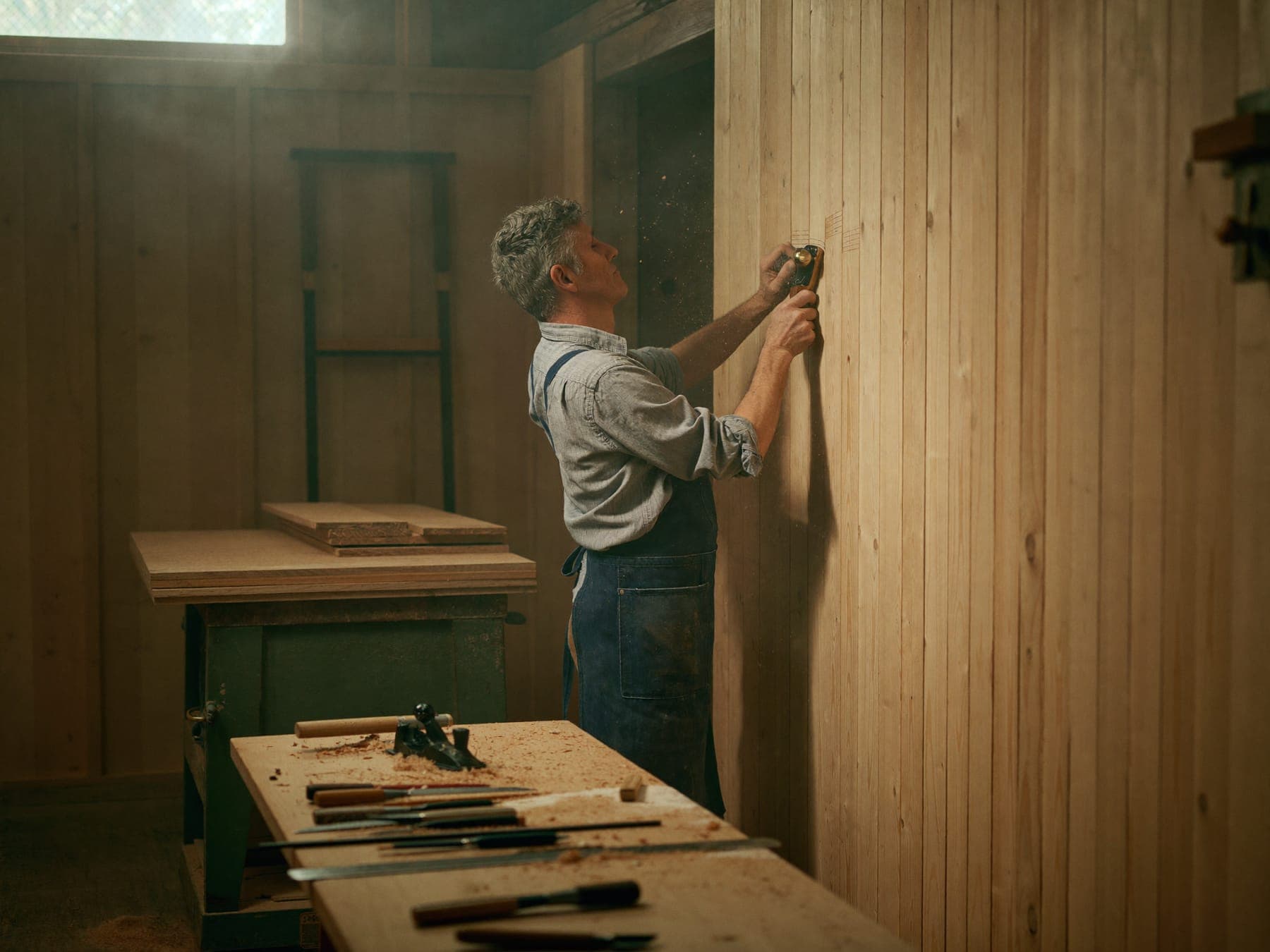 Joiner hand-finishing a timber wall panel in workshop